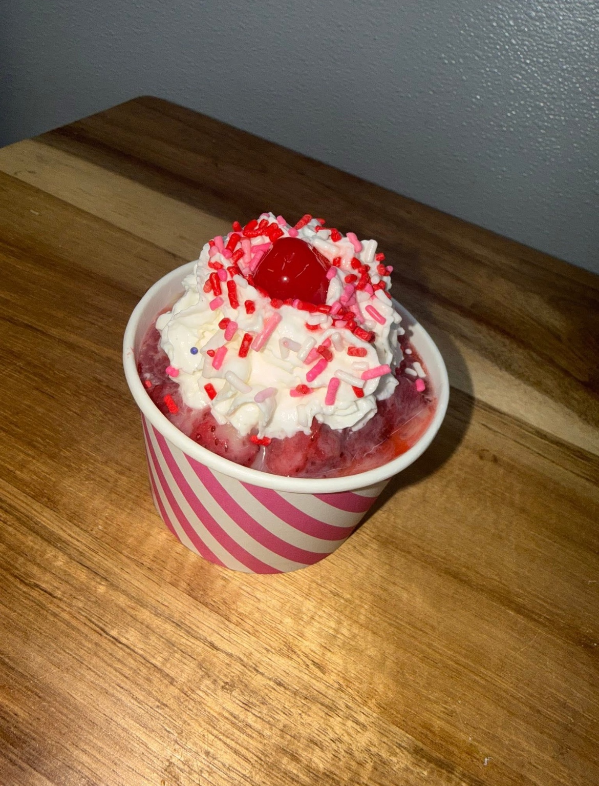 Strawberry frozen treat with whipped cream, sprinkles and a cherry